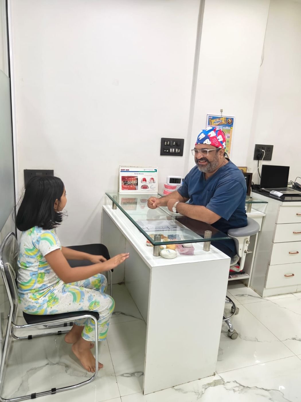 Dr. Gotise smiling as a young patient talks with him at the consultation desk